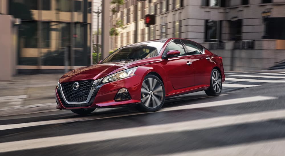 A red 2022 Nissan Altima is turning on a city street after getting a Bad credit car loan in Hudson County.
