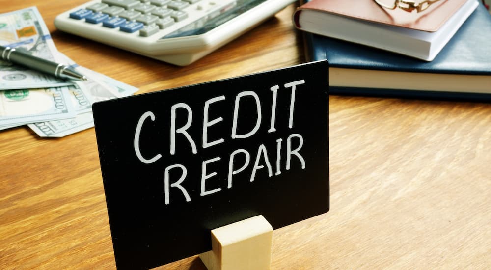 A small credit repair sign on a desk at a dealership that offers bad credit car loans in Hudson County.