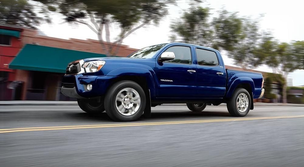 A blue 2015 Toyota Tacoma is shown driving on a city street.
